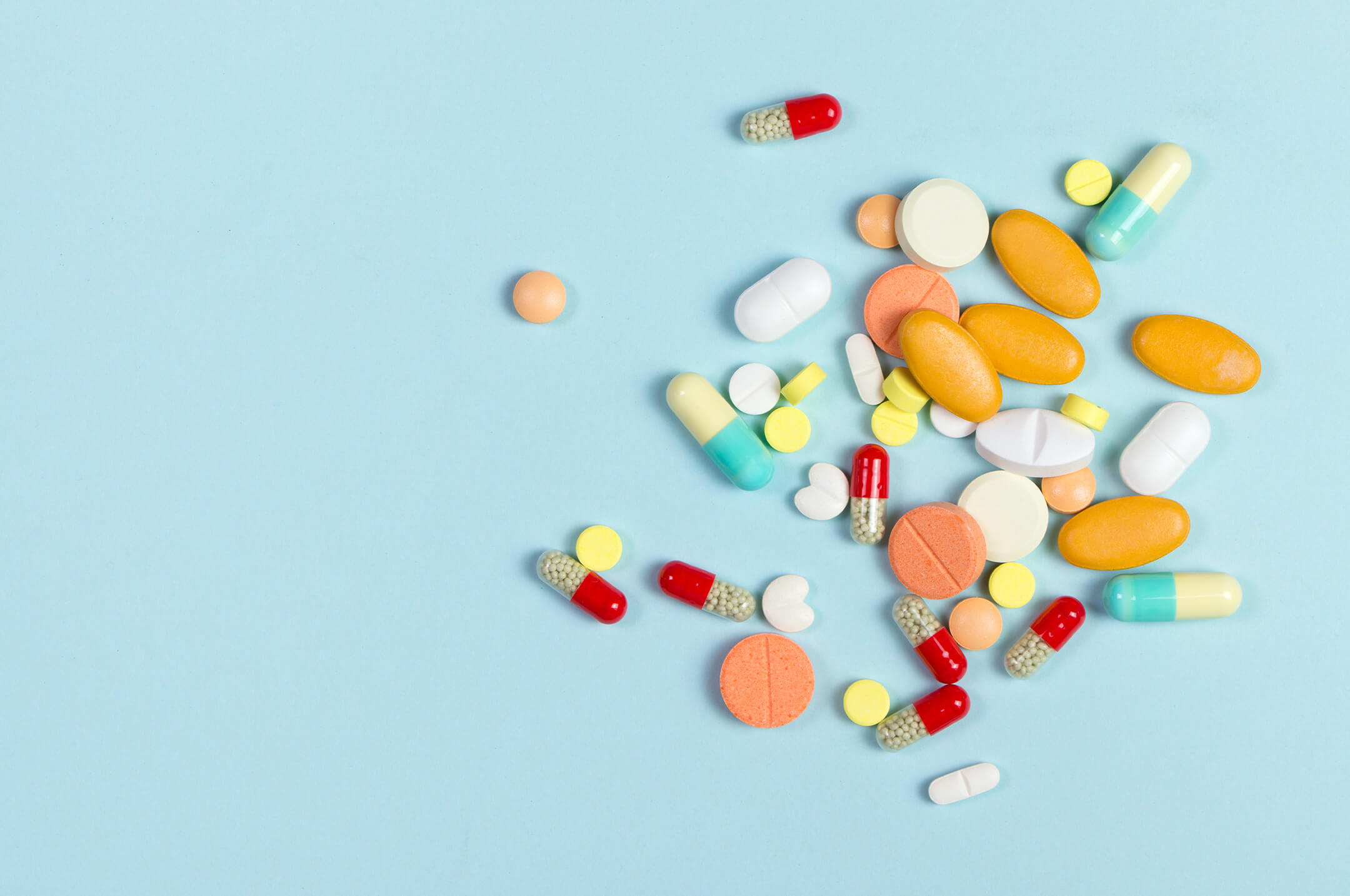 Pills and tablets spread across blue surface